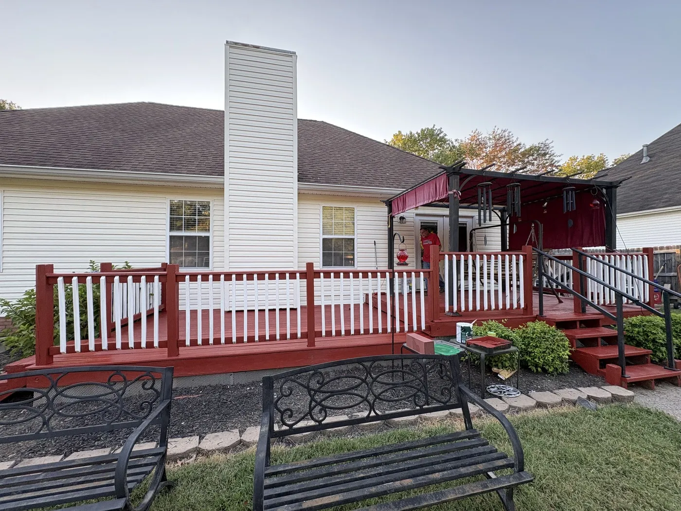 Red deck with white railings behind a white-sided home