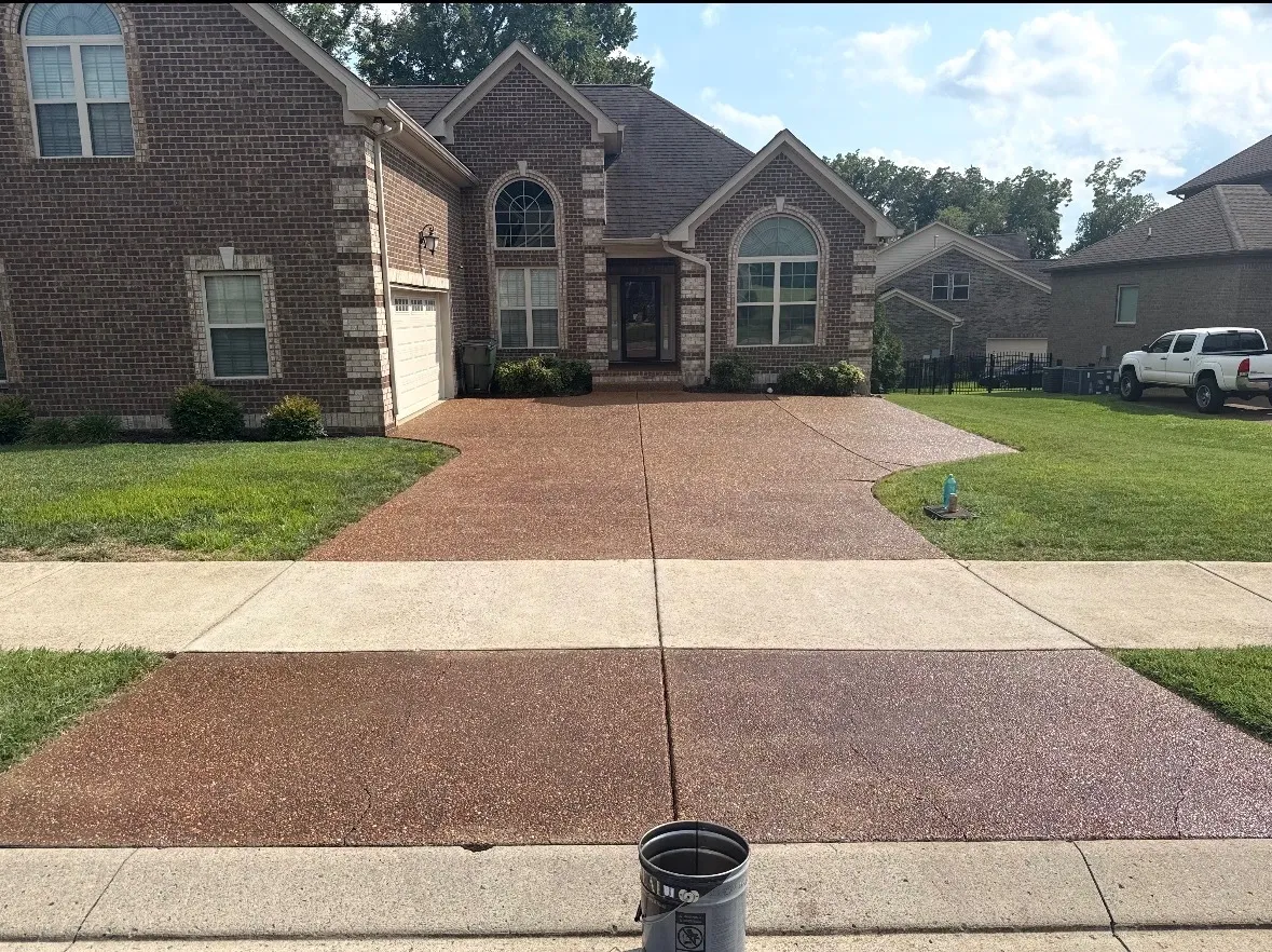 The same brick home with a freshly sealed reddish-brown driveway