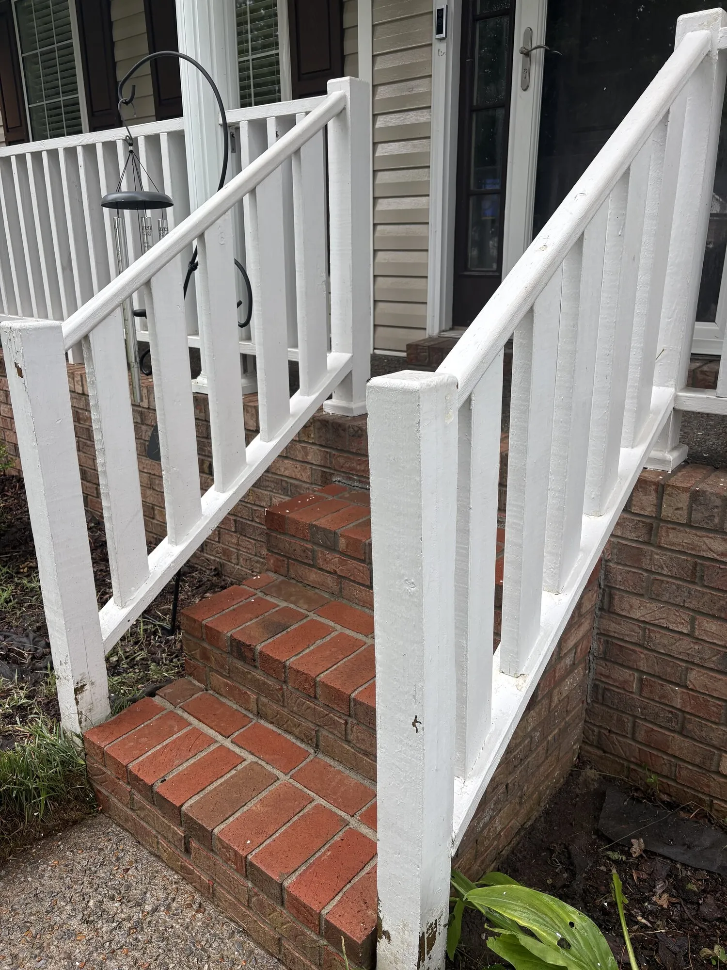 White railings along brick steps leading up to a front porch